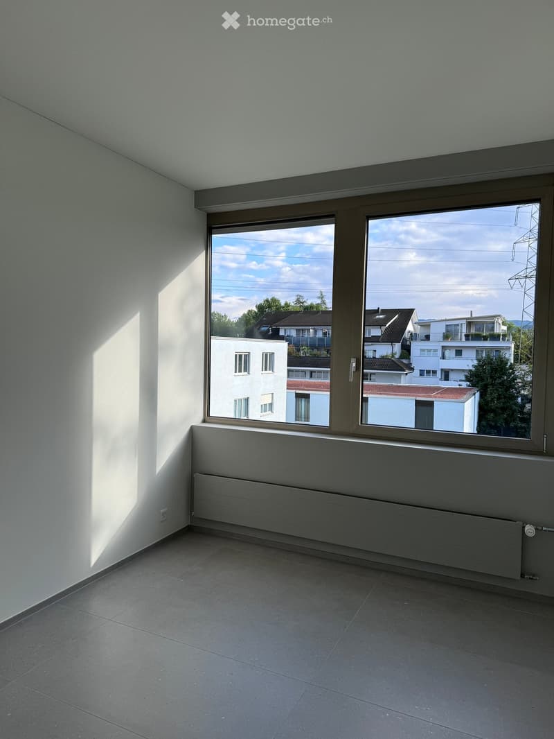 Empty room with large windows, tiled floor, radiator, and natural light from the window.