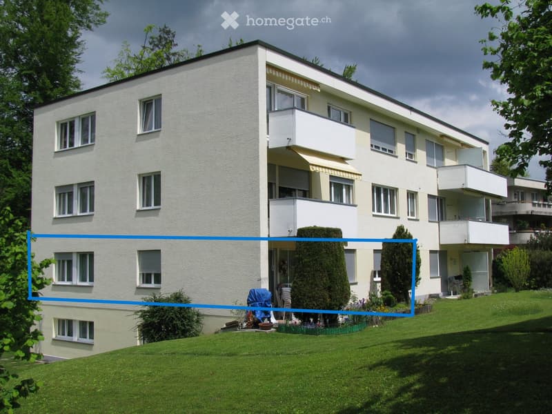 Two-story house with white exterior, multiple windows, balconies, and a well-maintained lawn.