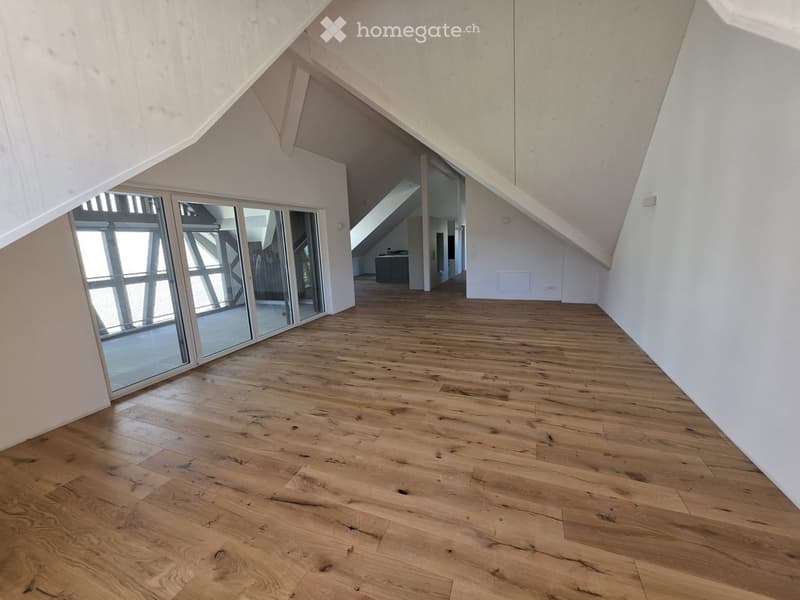 Empty room with wooden flooring, white walls, and large glass sliding doors leading to another space.