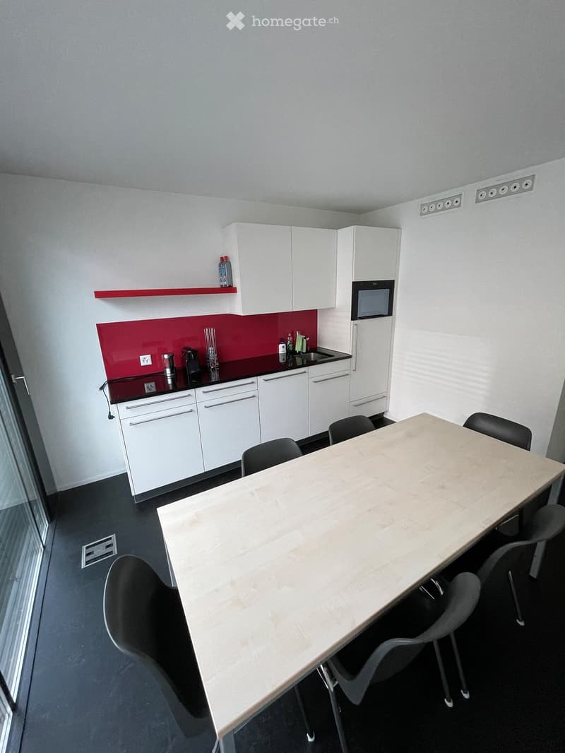 Kitchen with a long table, white cabinets, red countertop, microwave, refrigerator, power outlets, and a sink.