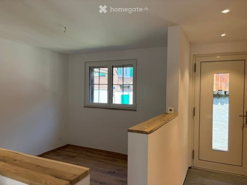 Empty room with wooden flooring, white walls, and a window with green shutters. No furniture or equipment present.