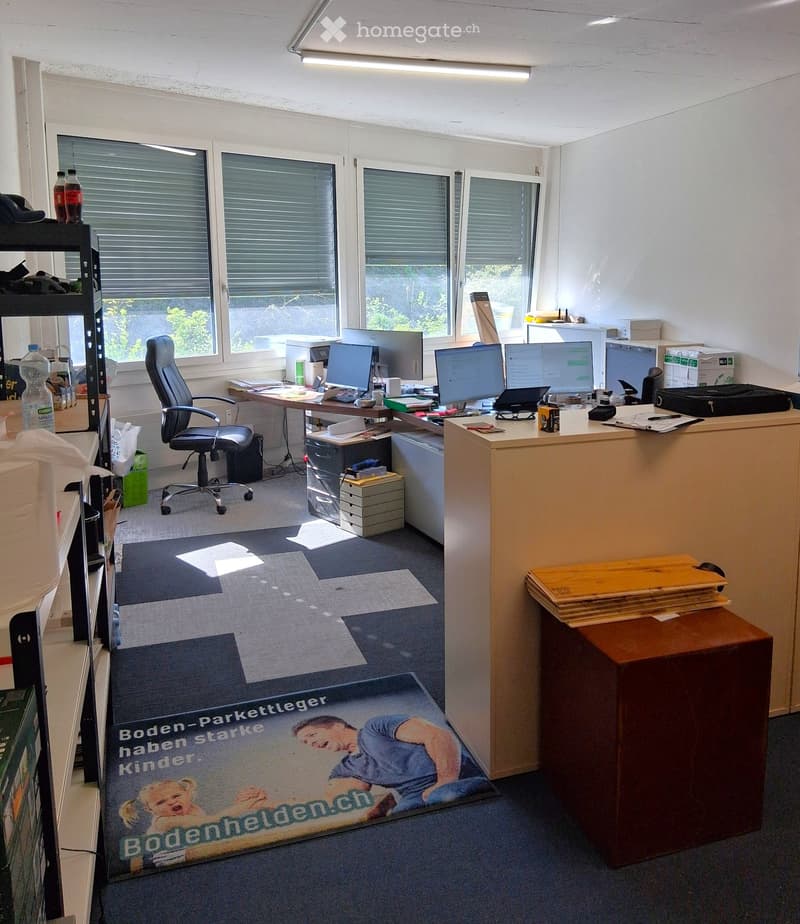 An office with a desk, computer monitors, and office supplies. A chair is placed near the desk. A mat is on the floor.