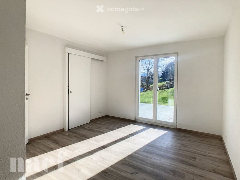 Empty room with wooden flooring, white walls, and a large sliding glass door leading to an outdoor area.