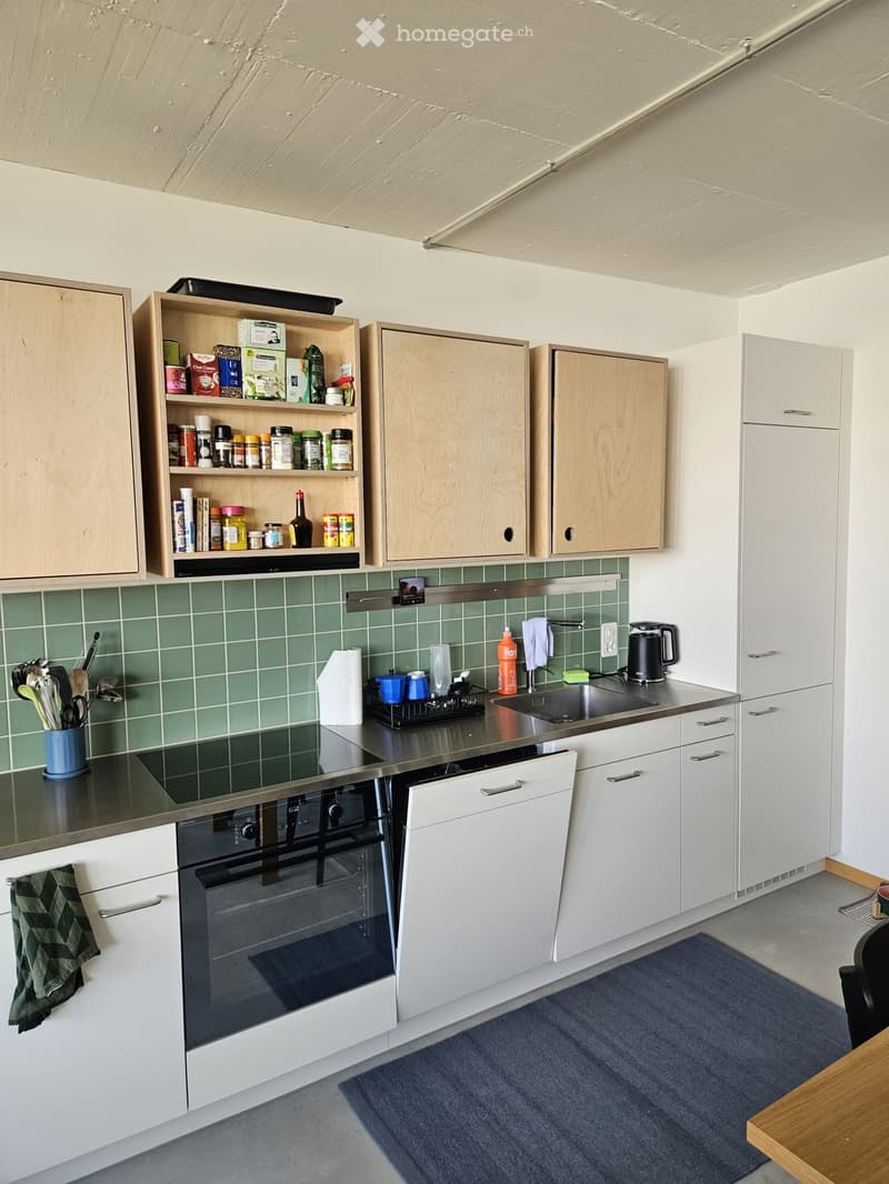 Modern kitchen with white cabinets, green tiled backsplash, stainless steel appliances, and various kitchen items on the counter.
