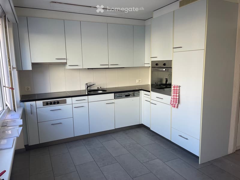 Modern kitchen with white cabinets, stainless steel appliances, and a black countertop.