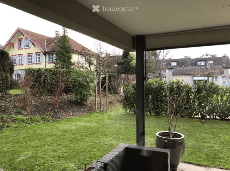 Garden with green lawn, potted plant, and outdoor seating area.