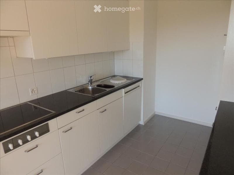 Modern kitchen with white cabinets, black countertops, stainless steel sink, and built-in oven.
