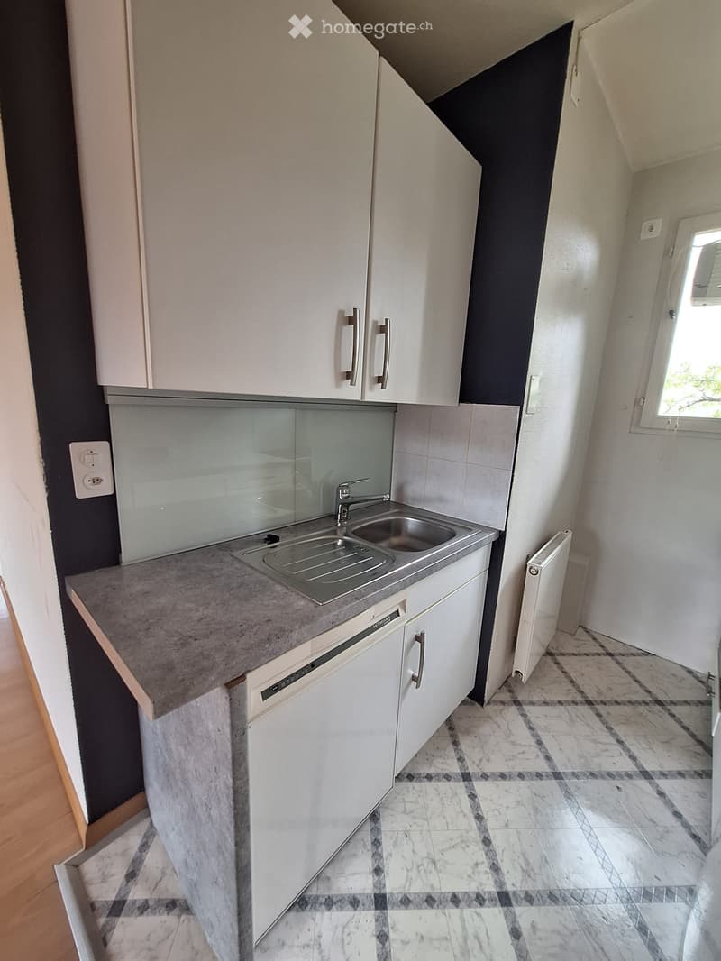 Modern kitchen with white cabinets, a stainless steel sink, and a dishwasher. The countertop is made of gray stone, and the floor features a marble tile pattern.