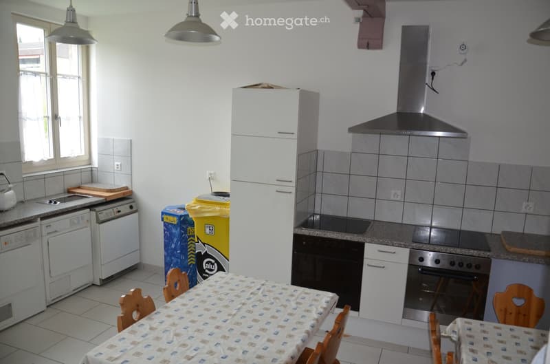 Modern kitchen with white cabinets, stainless steel appliances, granite countertops, and a dining area with a table and chairs.