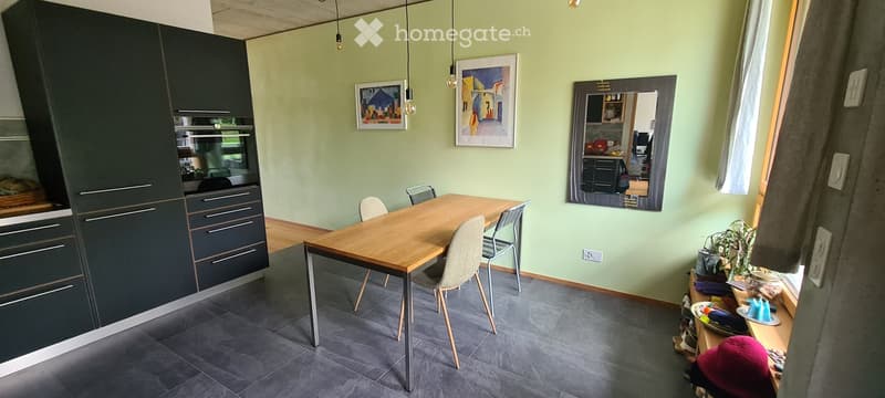 Dining area with a wooden table, chairs, dark cabinets, and a mirror on the wall.