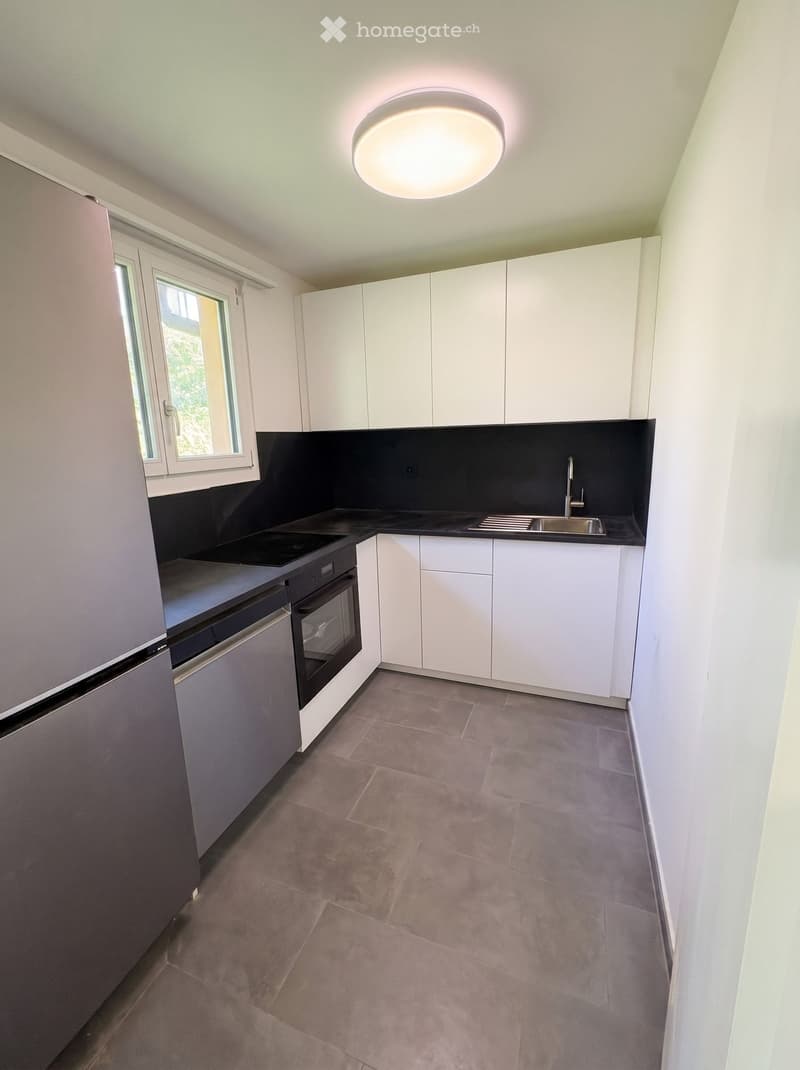 Modern kitchen with white cabinets, black countertops, stainless steel appliances, and a central island.