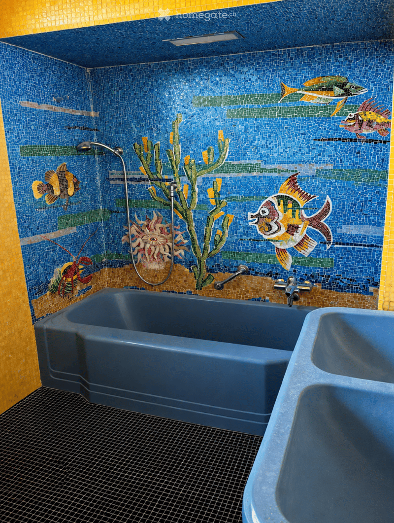 Bathroom with blue mosaic tile walls featuring an underwater theme with fish and coral designs, a blue bathtub, and a sink with a faucet.