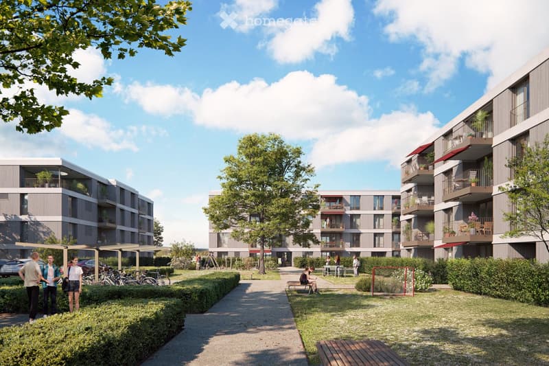 Modern residential complex with multiple apartment buildings, balconies, greenery, and outdoor seating areas.