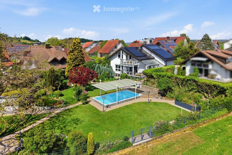 A well-maintained garden with a swimming pool, surrounded by greenery and a covered patio area. The property is part of a residential neighborhood with multiple houses and solar panels on the roofs.