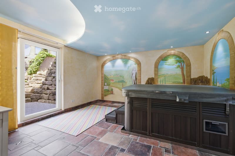 Spa room with a hot tub, painted mural walls, and a colorful striped rug.