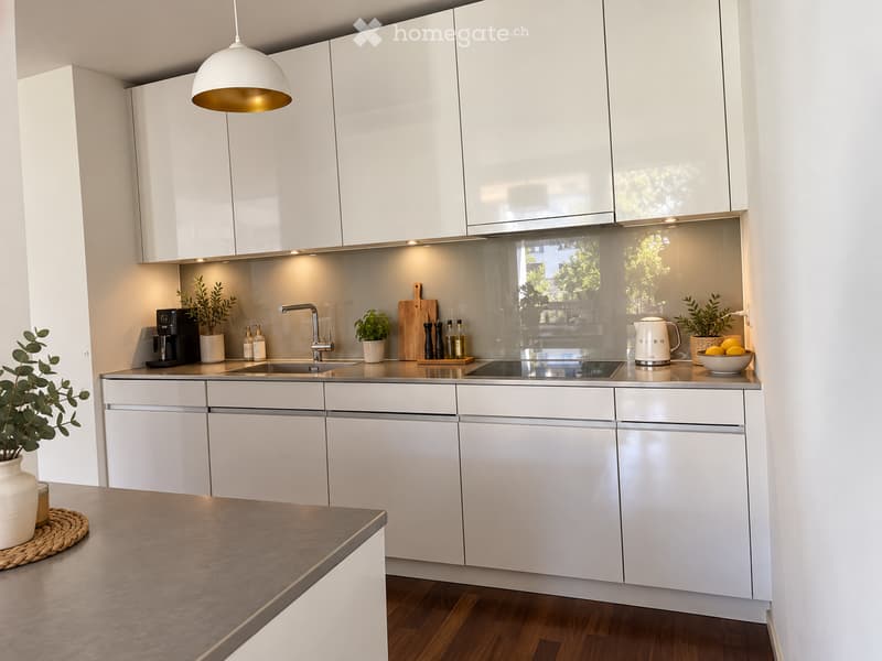 Modern kitchen with white cabinets, stainless steel appliances, and a central island with a wooden countertop.