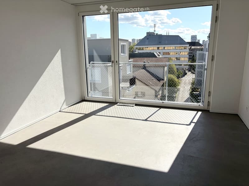 Empty room with large sliding glass doors leading to a balcony, light-colored walls, and a gray carpeted floor.