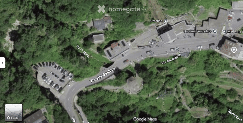 Aerial view of a large building complex surrounded by greenery, with labeled streets and parking areas.