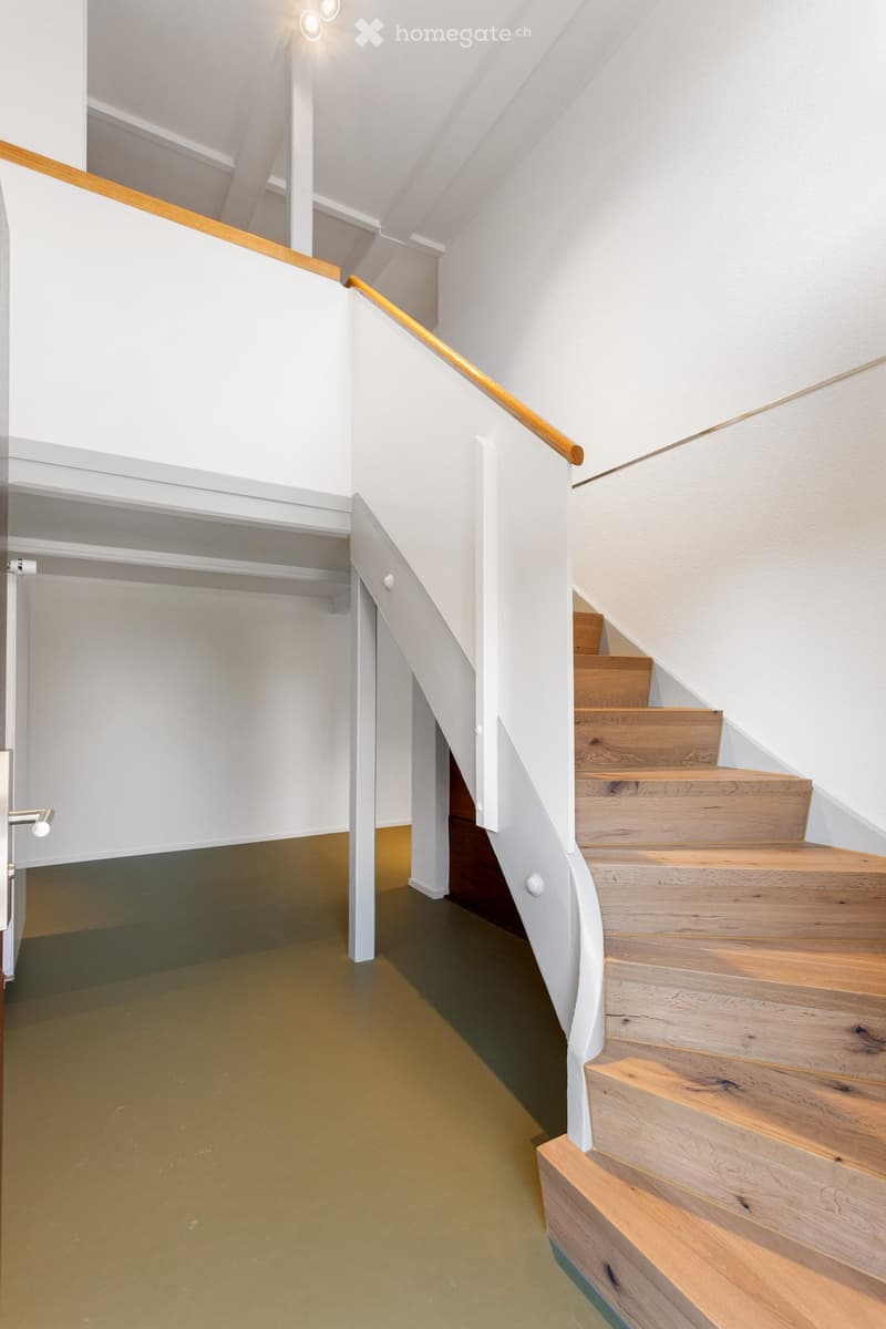 Modern hallway with a wooden staircase, white walls, and a glass door leading to another room.
