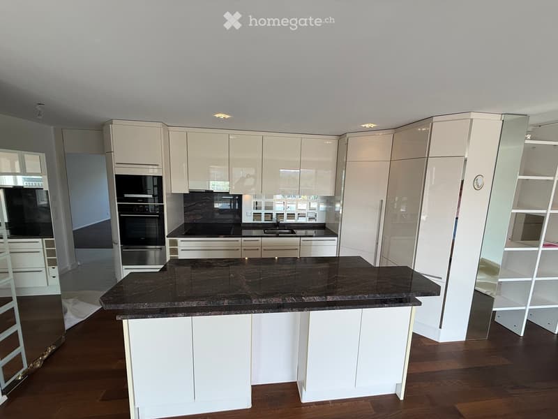 Modern kitchen with white cabinets, dark granite countertop, built-in oven, and stainless steel sink.