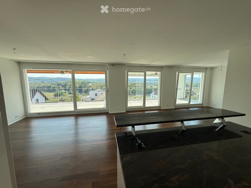 Bright, open room with wooden flooring, large sliding glass doors leading to a balcony, and a modern black table with metal legs.