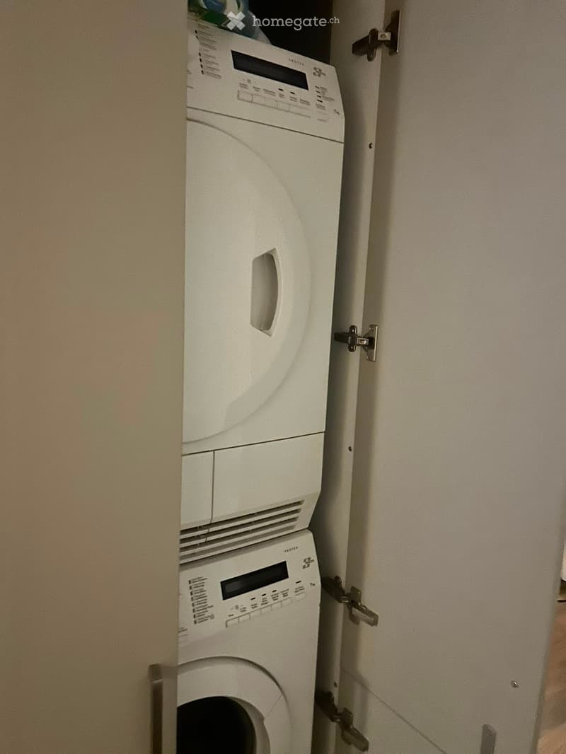 A compact bathroom with a white washing machine and a white dishwasher stacked vertically in a corner.