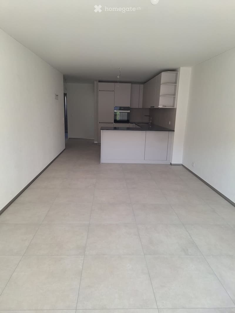 Empty kitchen with light grey cabinets, a black countertop, and tiled flooring. No appliances or furniture are present.