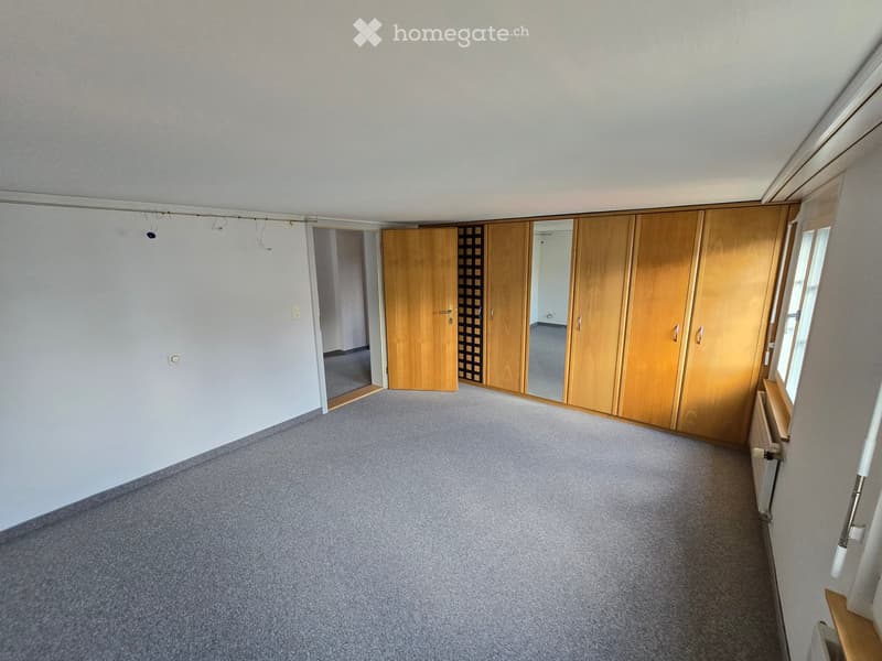 Empty room with light grey carpet, white walls, wooden closet, and a doorway leading to another room.