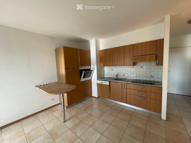 Modern kitchen with wooden cabinets, a built-in oven, dishwasher, sink, and a small wooden table.
