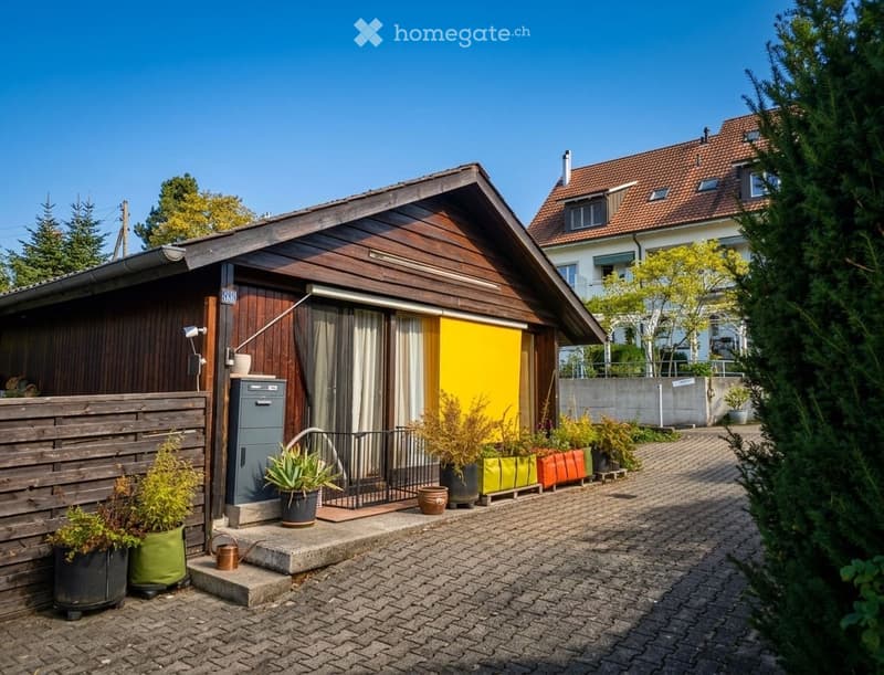 Single-story house with wooden exterior, yellow front door, and potted plants on the pathway.