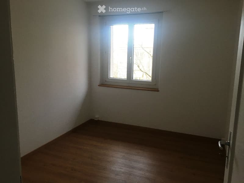 Empty room with wooden flooring, white walls, and a window with a simple wooden sill. No furniture or equipment present.