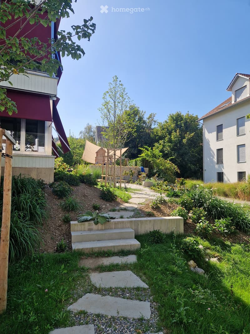 Garden with concrete steps, wooden play structure, and surrounding greenery.
