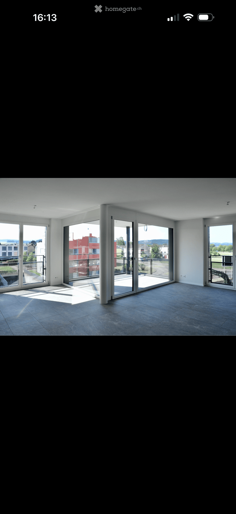 Empty room with large sliding glass doors leading to a balcony, tiled floor, and white walls.