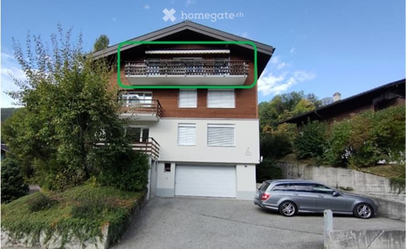 Two-story house with a garage, balconies, and a parking area.