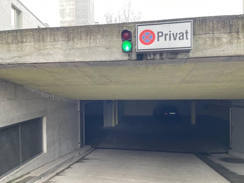 Underground garage, gray walls, green light, traffic sign for 'Private', concrete floor, parked car