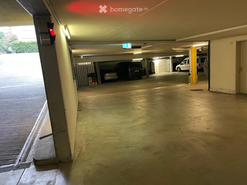 underground parking, light fixture, door, red stop sign, parked cars