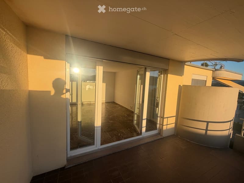 Balcony with tiled floor, glass sliding doors, and a view of the surrounding area.
