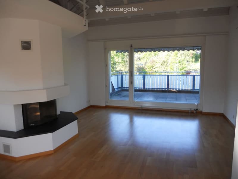 Empty room with wooden flooring, white walls, fireplace, and large sliding glass doors leading to a balcony.