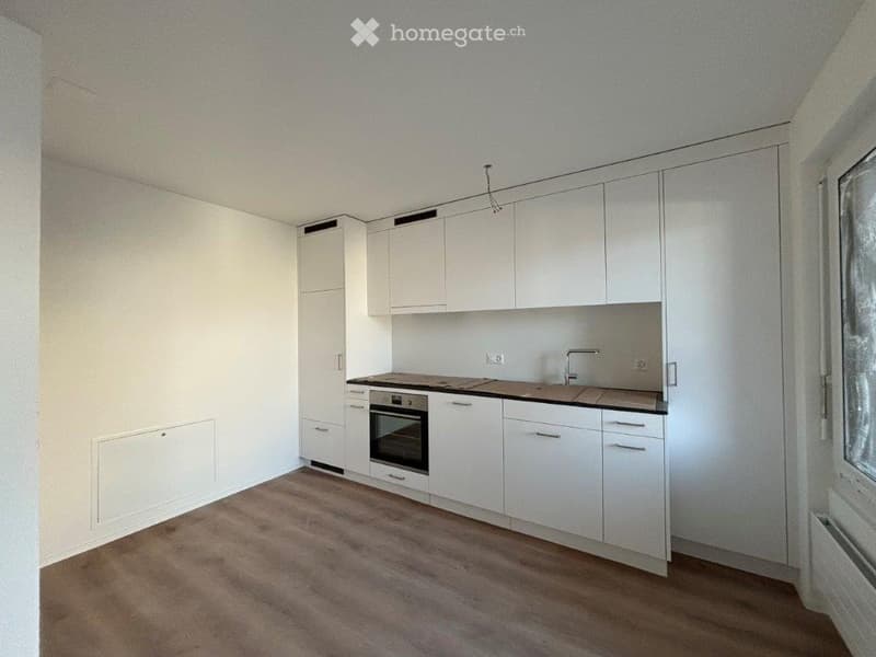 Modern kitchen with white cabinets, wooden countertop, and integrated oven. Features a sink with a modern faucet and ample storage space.