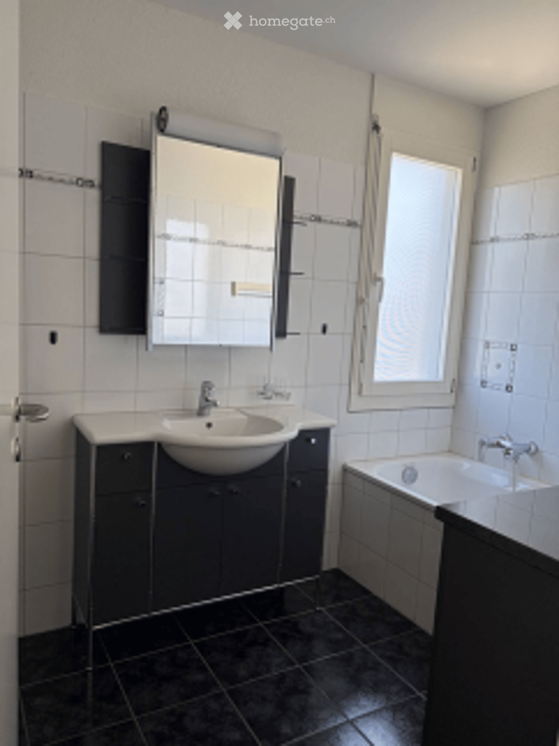 Modern bathroom with white tiles, black cabinetry, a sink, a mirror, and a bathtub.