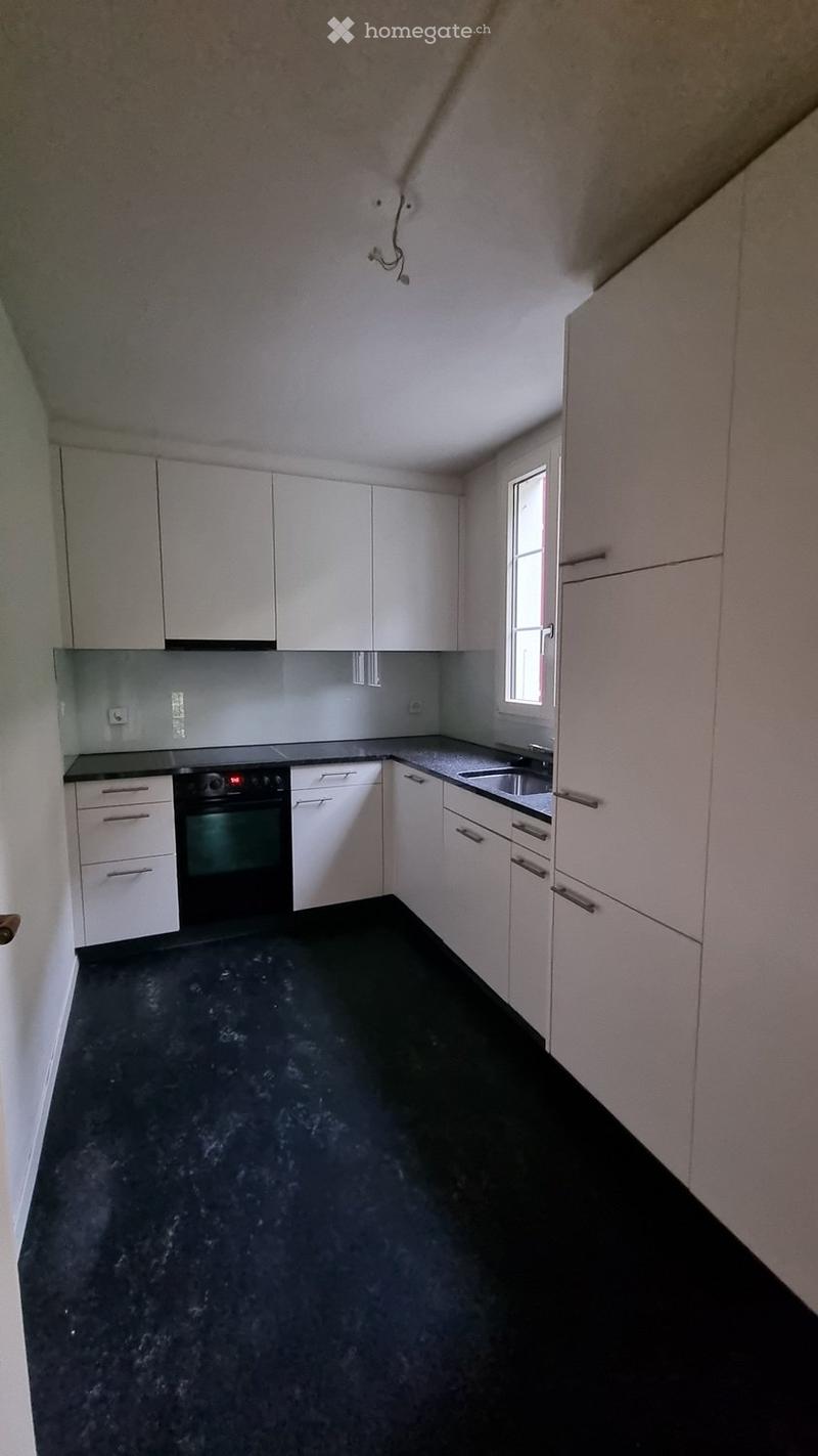 Modern kitchen with white cabinets, black countertops, and a black floor. Features an oven, sink, and ample storage space.