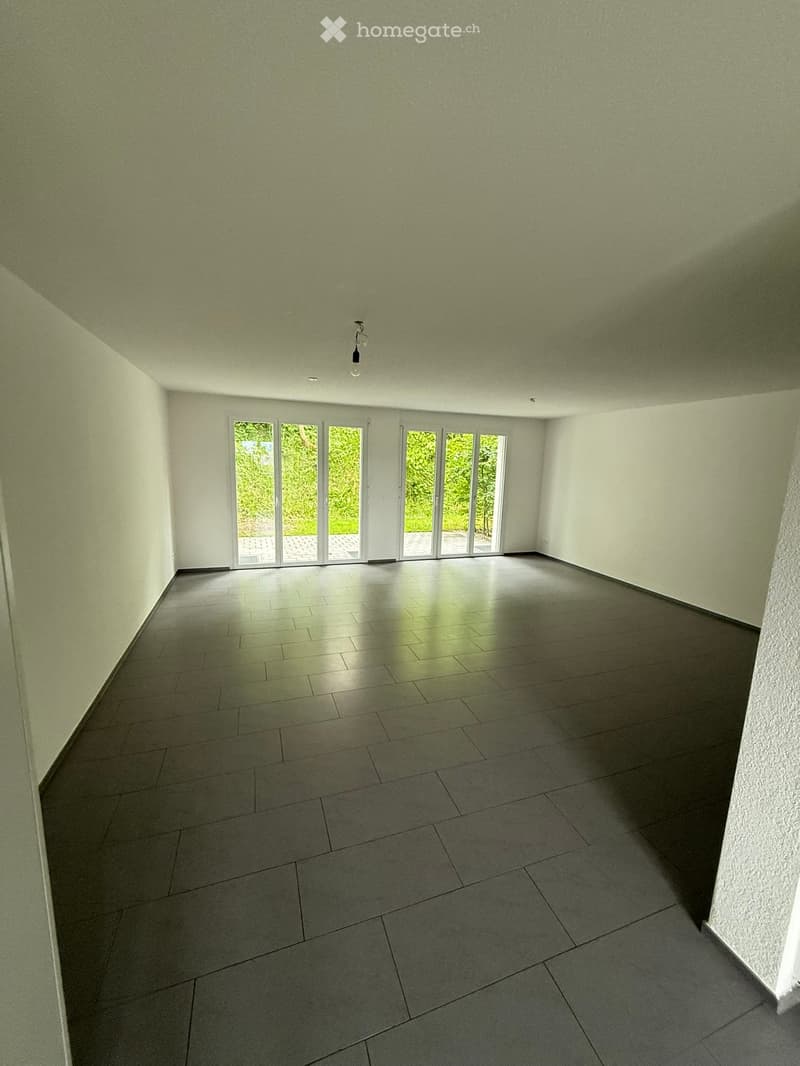 Empty room with light green walls, tiled floor, and large sliding glass doors leading to an outdoor area.