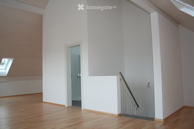 Empty room, wooden floor, white walls, windows, open door to bathroom