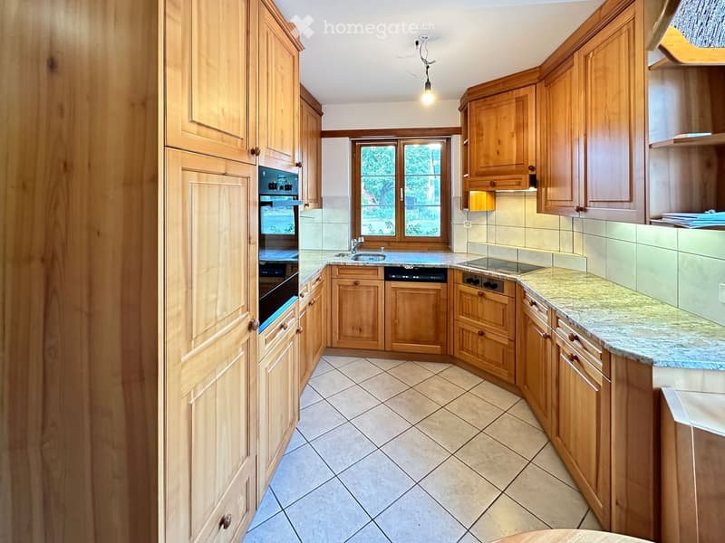Well-lit kitchen with wooden cabinets, granite countertops, and tiled flooring. Features include a sink, oven, dishwasher, and stove.