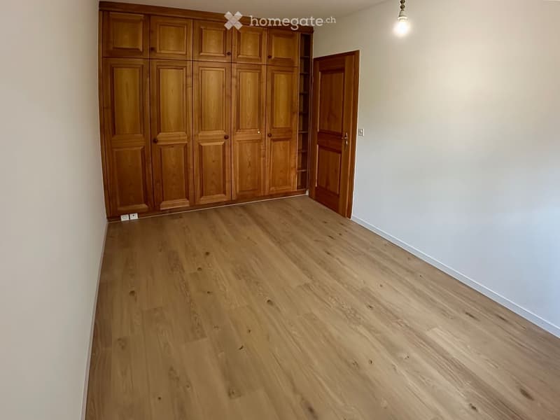 Empty room with light wooden flooring, light-colored walls, and built-in wooden wardrobes.