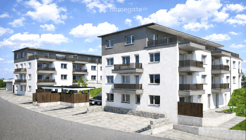 Modern multi-story residential building with white and grey facade, multiple balconies, and a paved entrance area.