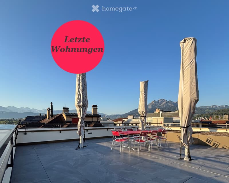 Roof terrace with outdoor dining setup, umbrellas, and scenic mountain view.