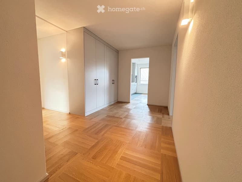 Empty hallway with wooden flooring, white walls, built-in closet, and recessed lighting.