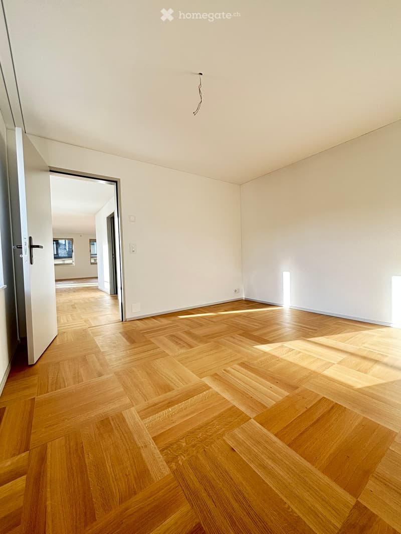 Empty room with light wooden herringbone flooring and white walls. No furniture or equipment visible.
