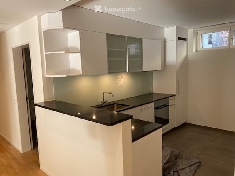 Modern kitchen with white cabinets, black countertops, and built-in appliances including a sink and oven.